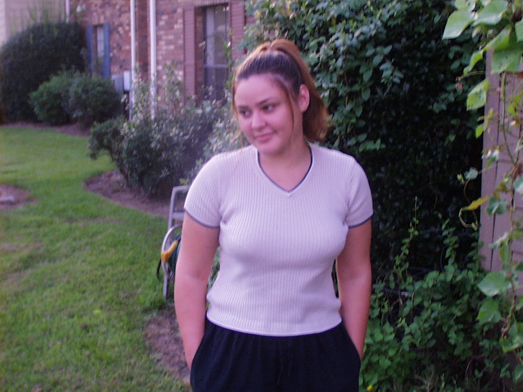 Young Faye in a light shirt standing outside the brick apartment building on Stumberg Lane