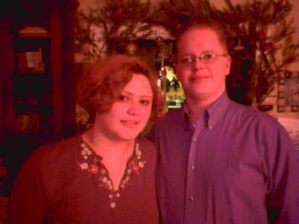 Faye in red with Jim in front of a Christmas tree