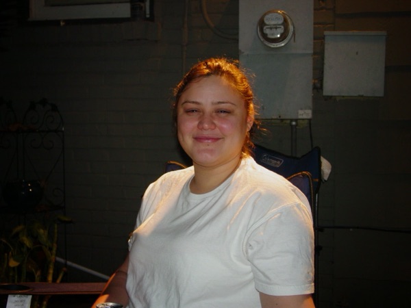 Faye smiling in a white T-shirt on a porch at night in Jackson